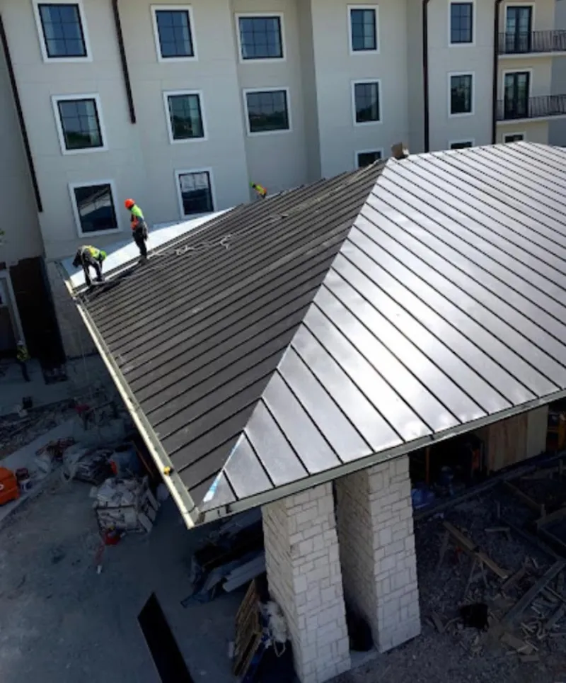 Crew installing standing seam metal roof panels on a commercial project in Westland